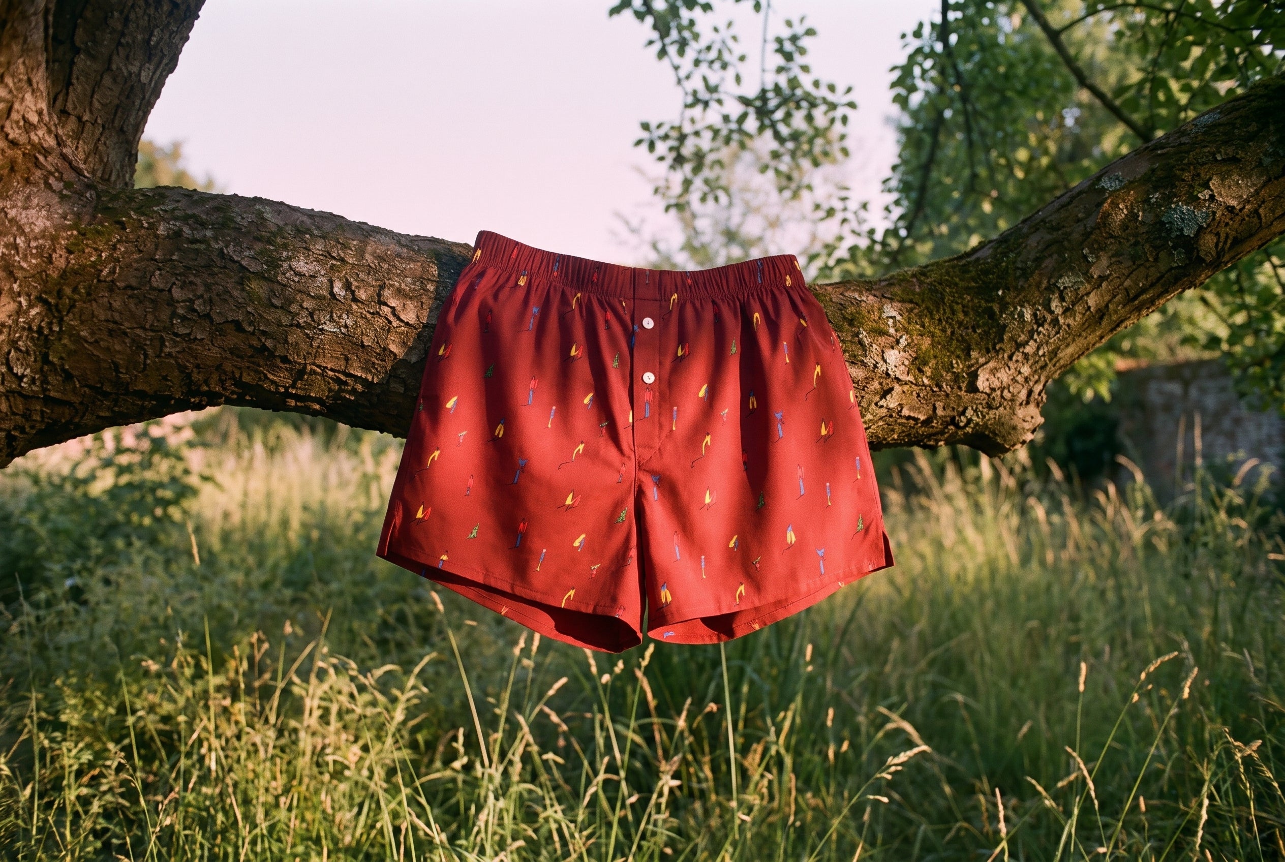 The KAYA x Mulehet cotton boxer in Brick Red hung over a tree branch at dusk